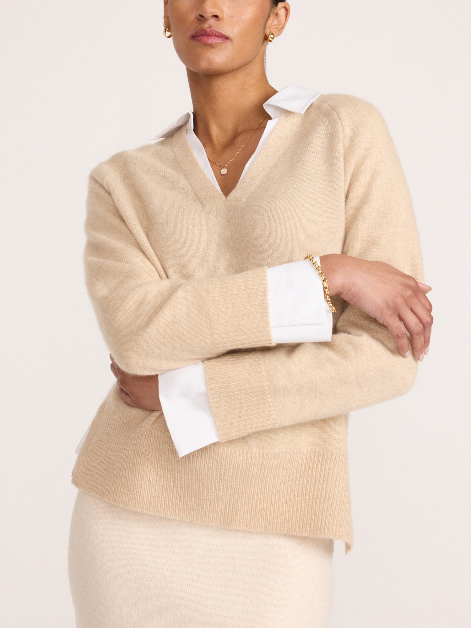 Ella layered looker sweater in sandstone melange, a V-neck ribbed knit with contrasting white cuffs and collared shirt underneath, paired with a cream skirt.