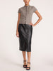 Woman wearing the Emmy cotton-wool cardigan in otter melange with a black croc-embossed midi skirt and strappy heels.