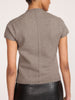 Back view of a woman wearing the Emmy cotton-wool cardigan in otter melange, paired with a black crocodile-embossed skirt.