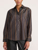 Front view of a woman wearing the Brochu Walker Everyday Shirt in Sedona Stripe, an unbuttoned charcoal cotton shirt with tan stripes over black leather pants.