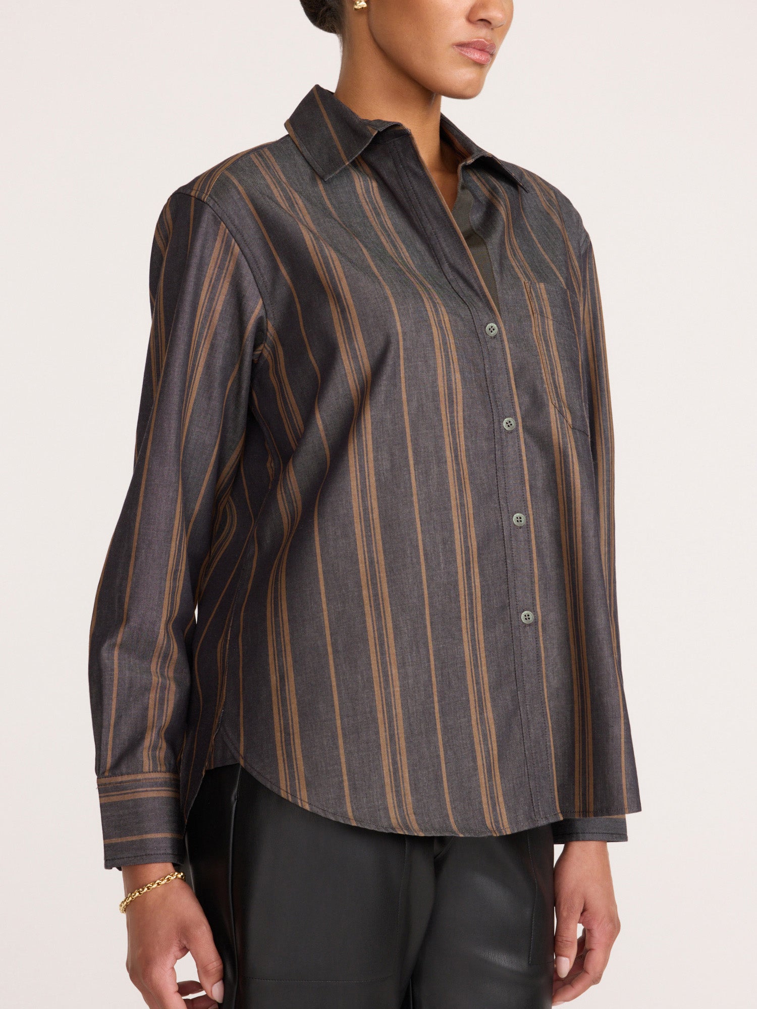 Side view of a woman wearing the Brochu Walker Everyday Shirt in Sedona Stripe, a buttoned charcoal cotton shirt with tan stripes paired with black pants.