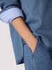 Stylish ladies top in medium-wash denim with a rolled striped cuff detail and hand tucked into denim trouser pocket.