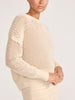 Side view of the ecru open-knit pointelle crewneck sweater, showing the airy stitch pattern and dropped shoulder.