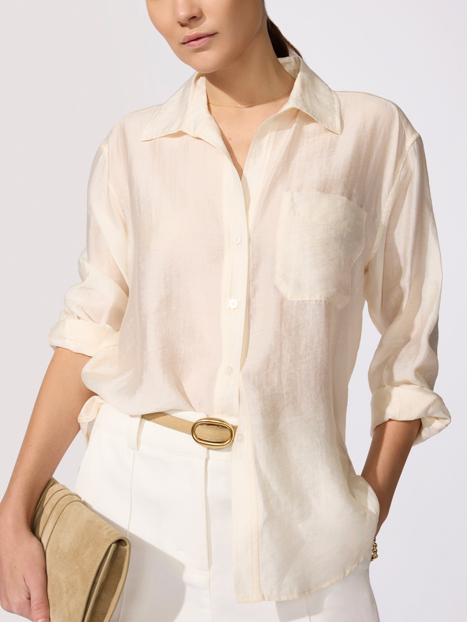 White classy outfit featuring a cream linen button-front shirt with a chest pocket and rolled sleeves tucked into white trousers with a tan belt.