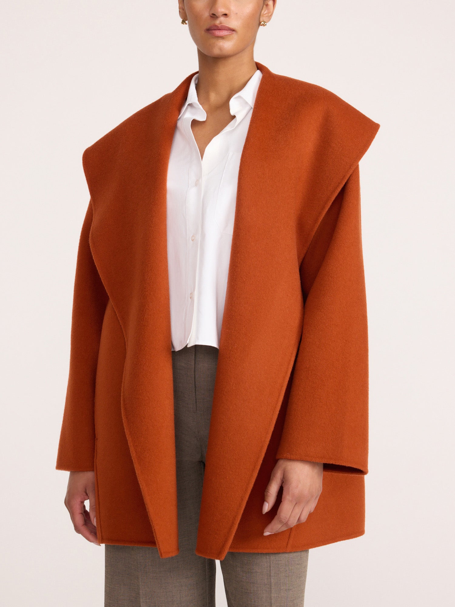 Front view of a woman wearing the Brochu Walker Finley Coat in Canyon Orange, an oversized open-front wool coat over a white shirt and gray trousers.