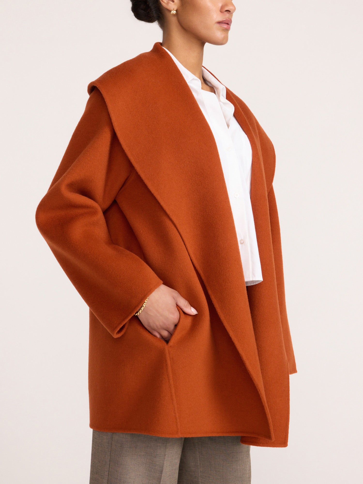 Woman wearing the Brochu Walker Finley Coat in Canyon Orange, an oversized wool coat worn open over a white blouse and gray trousers.