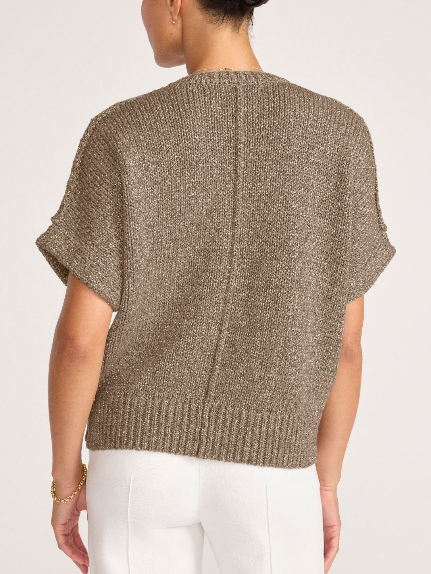 Back view of the bronze Gaia Metallic Tee, a boxy short sleeve sweater, styled with ivory women's pants.