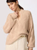 Classy women's sweater in sand-toned chunky cable knit with a V-neckline, wide sleeves, and ribbed hem styled with cream trousers and a tan belt.