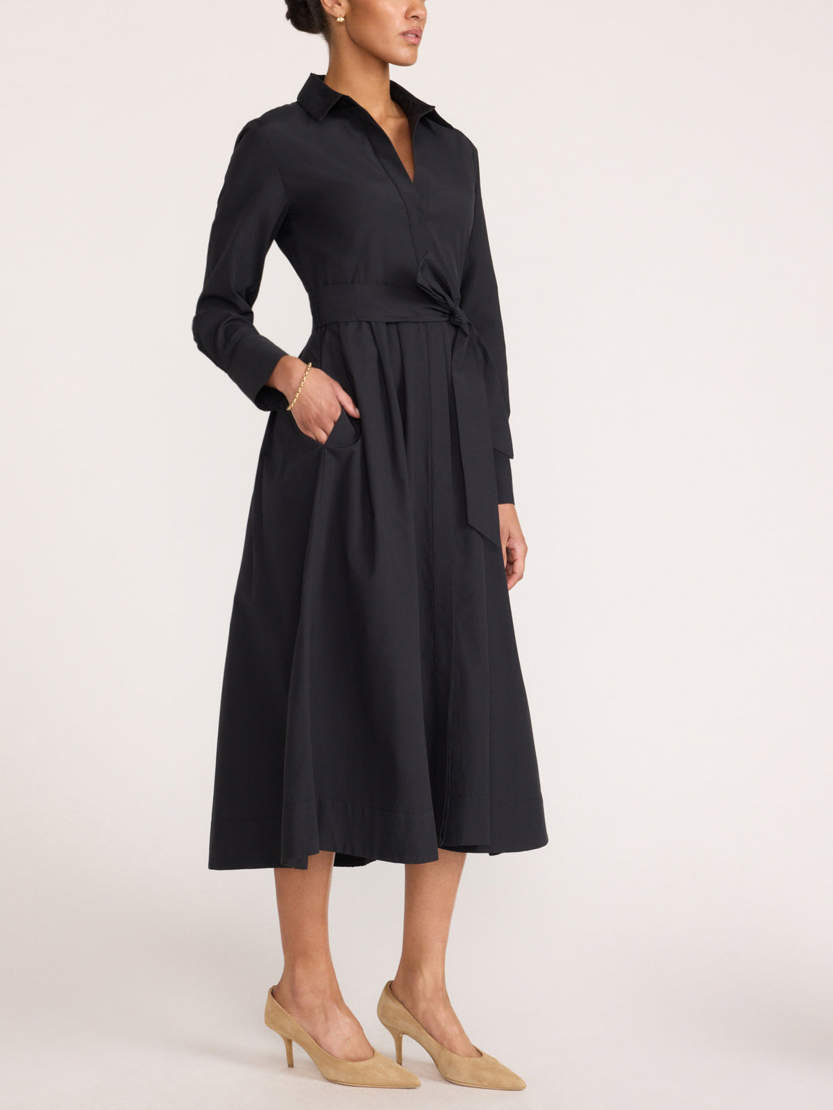Women's black midi shirt dress with a tie waist and side pockets, styled with beige heels