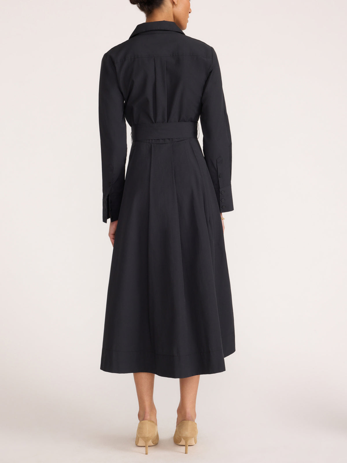 Back view of a women's black midi shirt dress with a waist belt, styled with heeled shoes