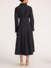 Back view of a women's black midi shirt dress with a waist belt, styled with heeled shoes