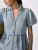 Classy chic dress in chambray denim with puff sleeves, deep V-neckline, and button-front bodice shown in close-up.