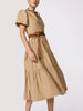 Woman in an elegant beige tiered midi shirtdress with puff sleeves, cinched at the waist with a brown leather belt.