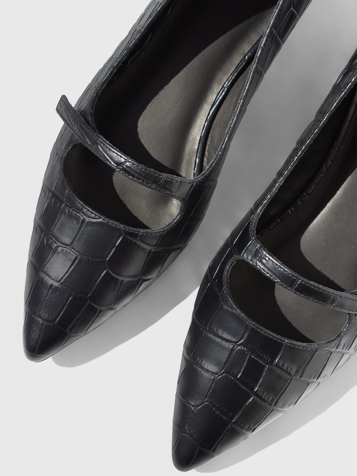 Close-up of black croc-embossed Mary Jane flats, showing the pointed toe and instep strap