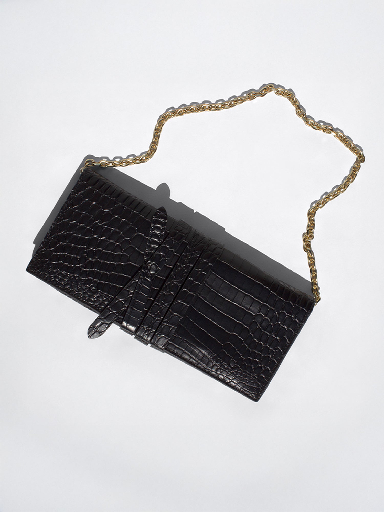 Black crocodile-embossed clutch bag with a gold chain strap, flat product shot