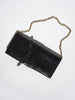 Black crocodile-embossed clutch bag with a gold chain strap, flat product shot