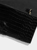 Close-up of a black crocodile leather clutch bag corner with gold-tone hardware detail