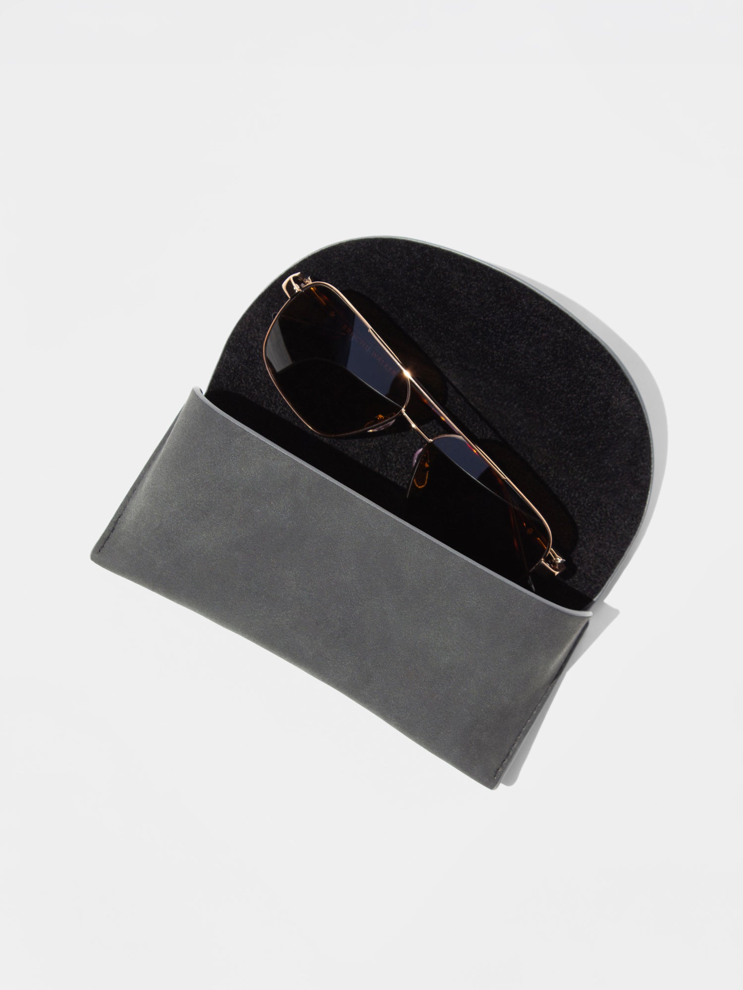 Gold-frame aviator sunglasses tucked inside a soft gray foldover case