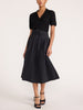 Isola dress in black onyx, full-length front view with pleated tie-waist midi skirt and strappy heels