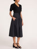 Isola dress in black onyx, side view with tie-waist midi skirt, side pockets, and platform sandals