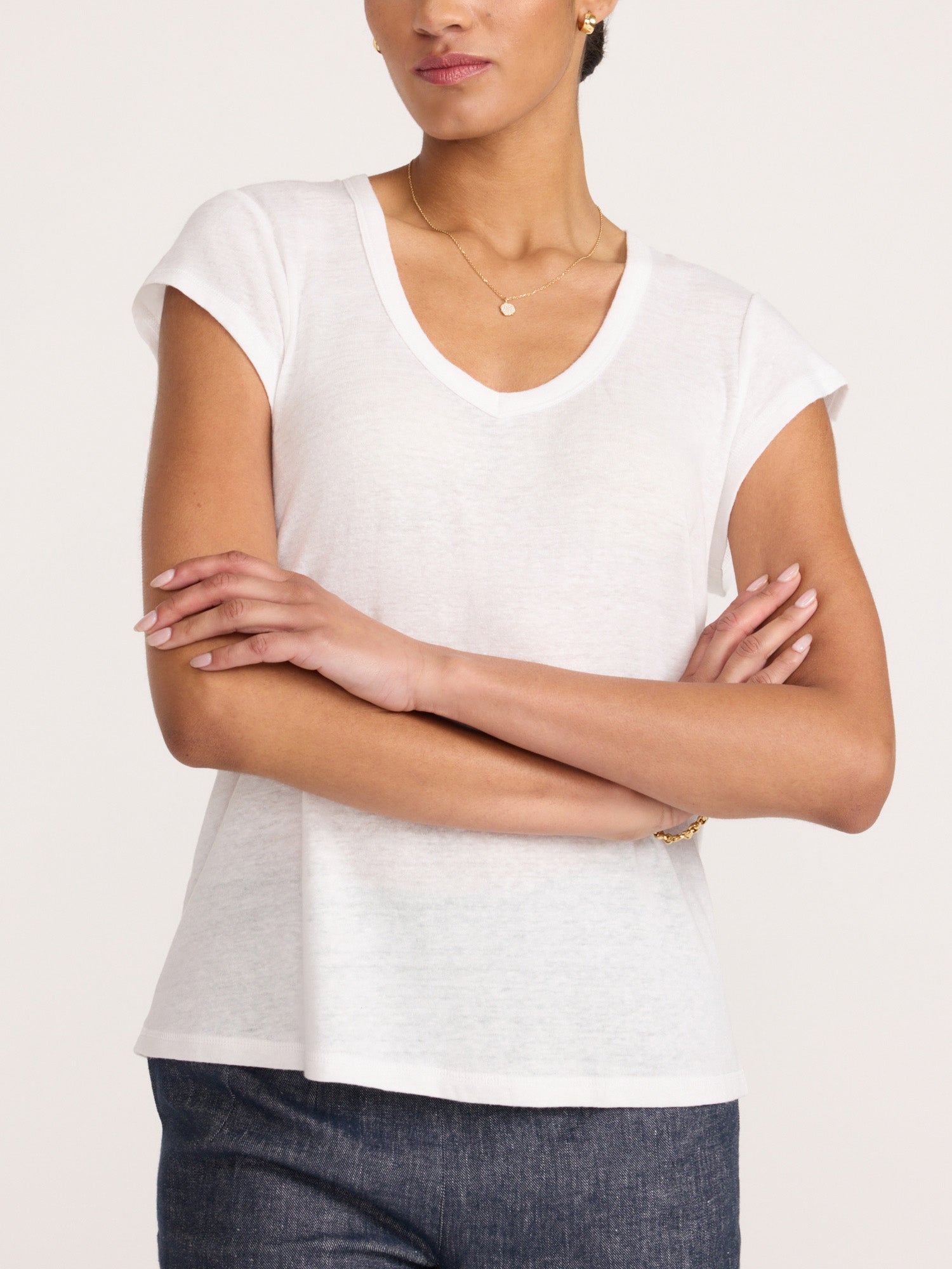 Model with arms crossed wearing the white Koda V-neck short sleeve tee with dark denim.