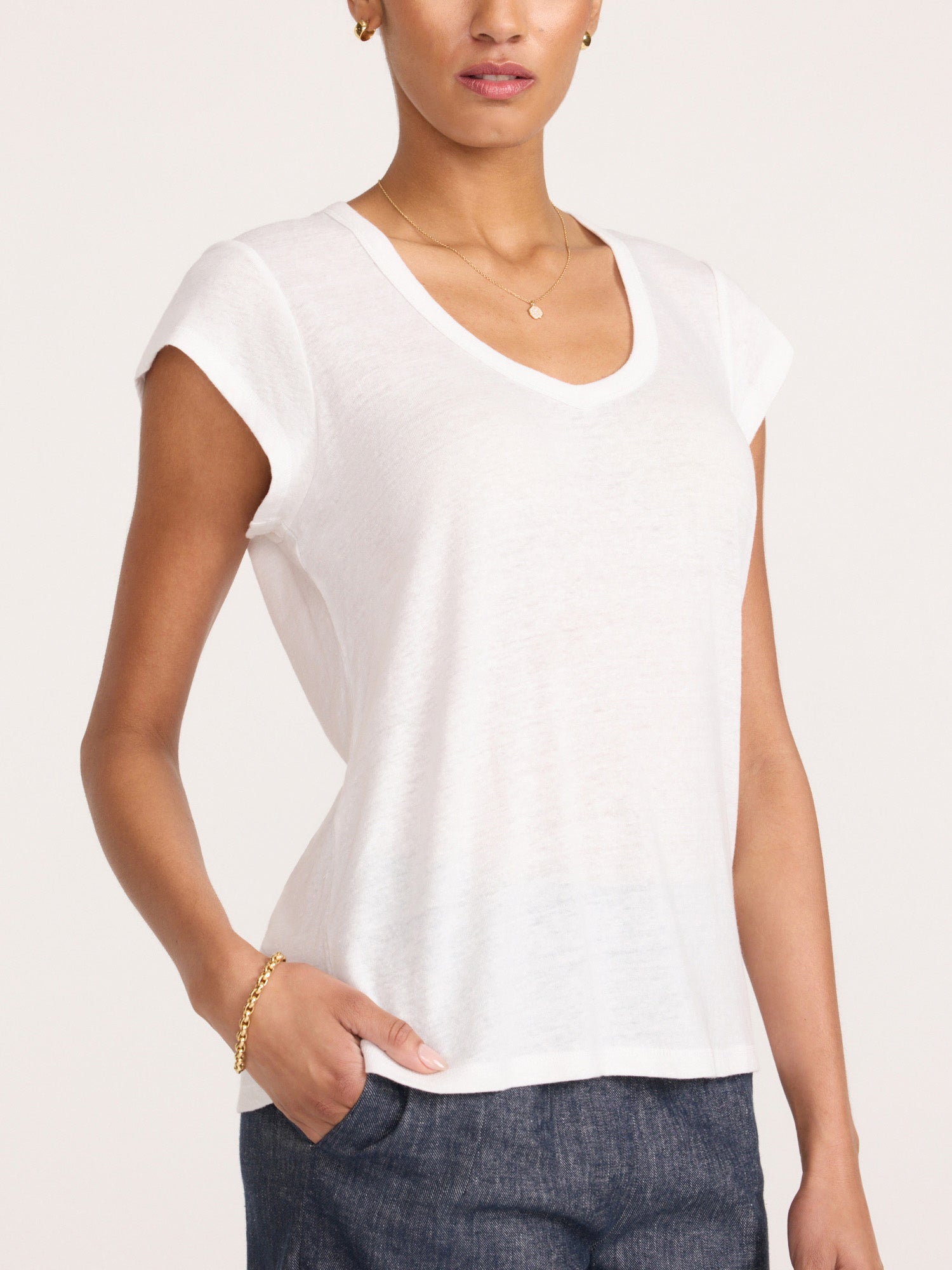 Model wearing the Koda women's white short sleeve V-neck tee tucked into indigo denim.