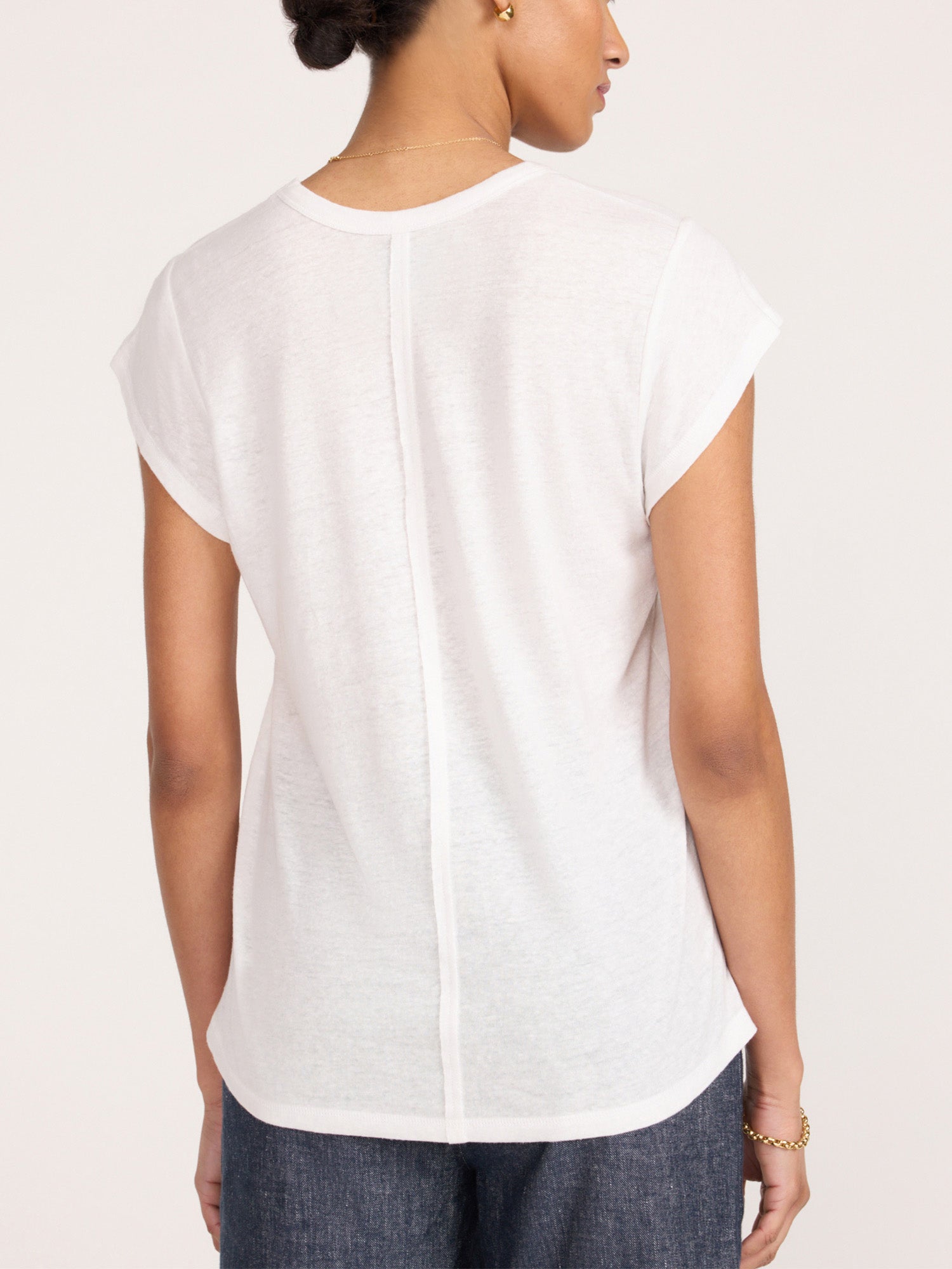 Back view of a model in the white Koda short sleeve tee styled with indigo jeans.