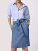 Denim shirt for women in a blue pinstripe worn tucked into a medium-wash denim paper-bag midi skirt with a self-tie bow waist.