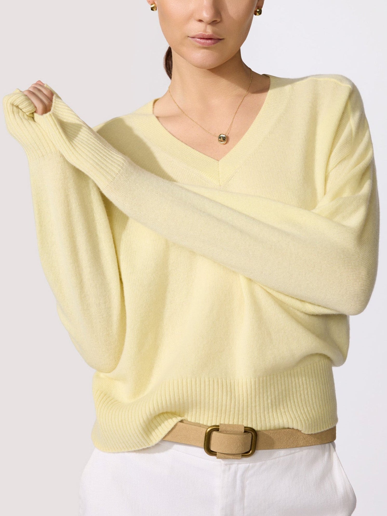 Classy women's sweater in pale yellow cashmere with a V-neckline, dolman sleeves, and ribbed hem shown in a close-up upper-body view.