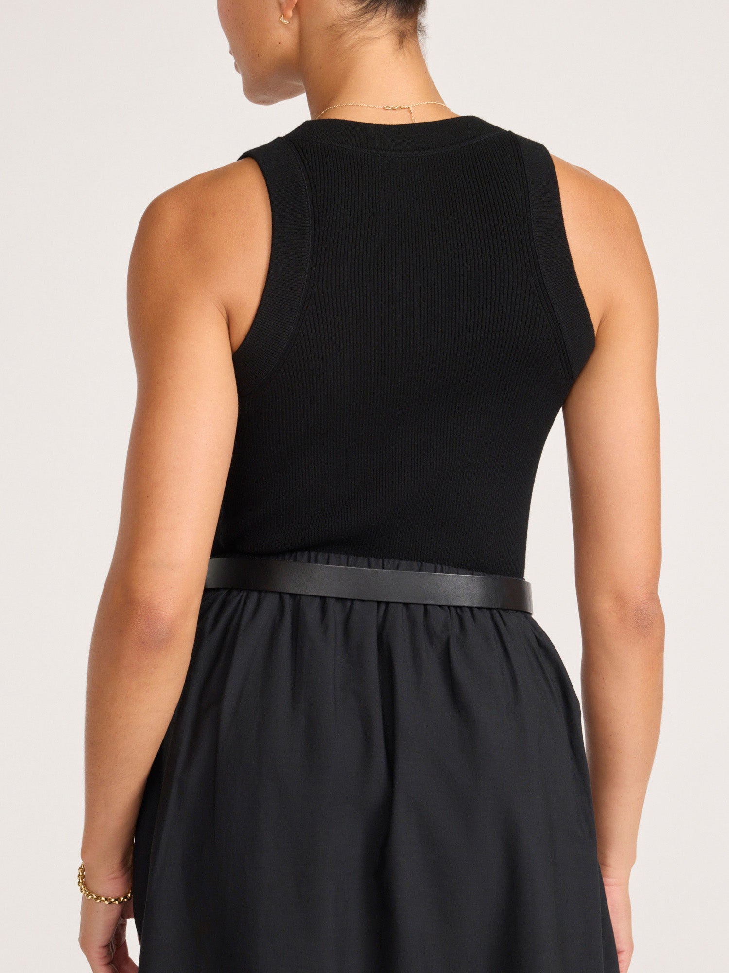 Back view of the black Leo Tank tucked into a black skirt with a black leather wrap belt.