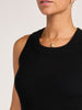 Close-up of the black Leo Tank showing its ribbed knit and scoop neckline, styled with a gold pendant necklace.