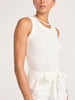 Angled view of a model wearing the white ribbed Leo Tank with a pearl necklace and ivory bow-tie bottoms.