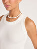 Close-up of the white ribbed Leo Tank with a scoop neckline, styled with layered pearl necklaces.