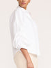 Milan oversized white button-up shirt in salt white, side view with beige pants
