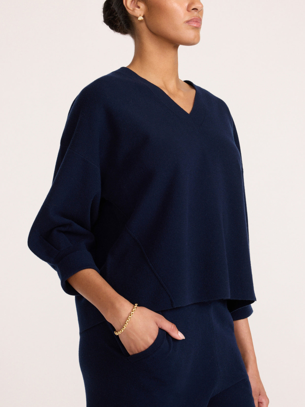 Side profile of a women's navy blue V-neck knit top with three-quarter sleeves and matching bottoms
