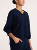 Side profile of a women's navy blue V-neck knit top with three-quarter sleeves and matching bottoms