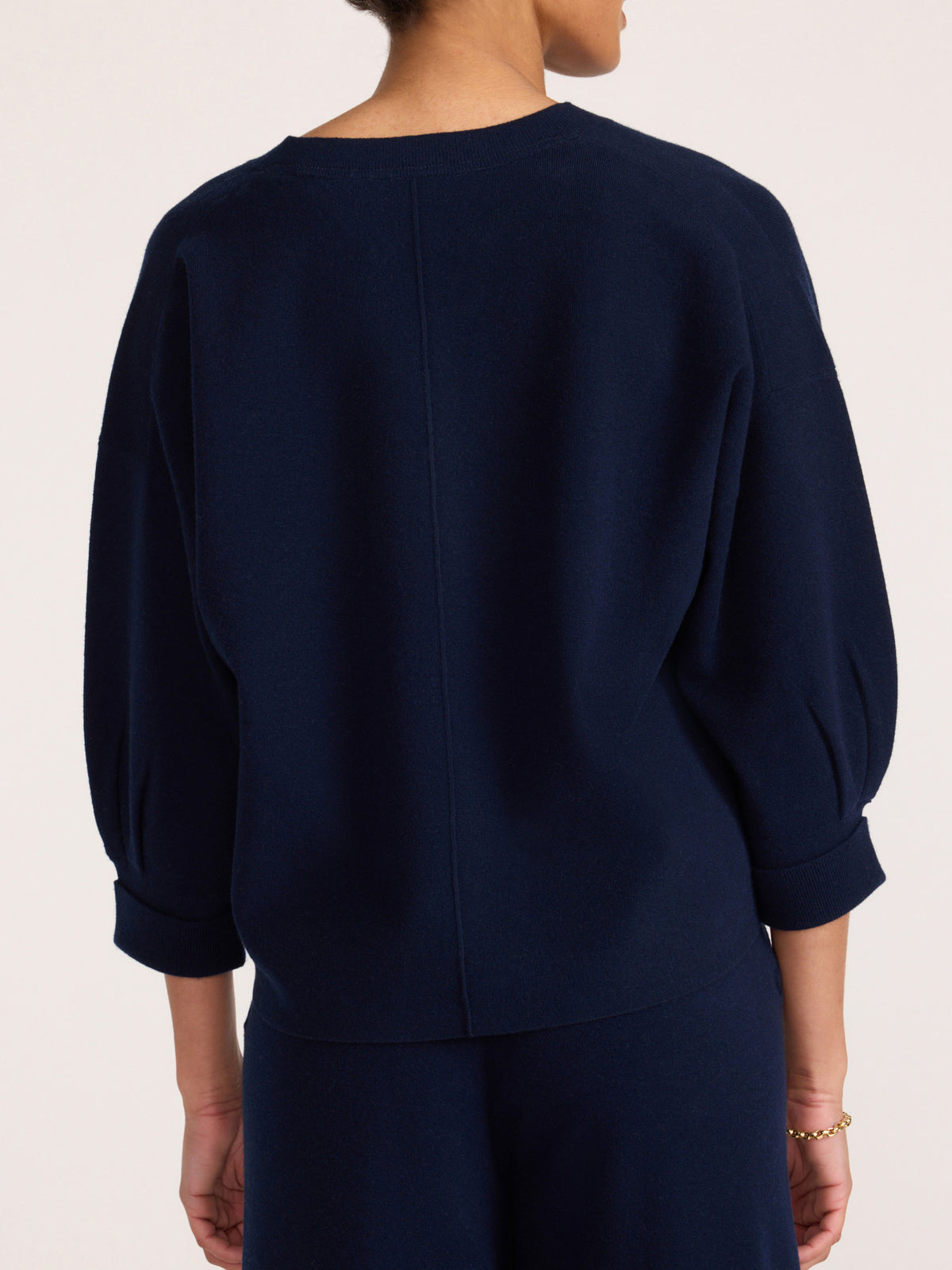 Back view of a women's navy blue V-neck knit sweater with three-quarter balloon sleeves