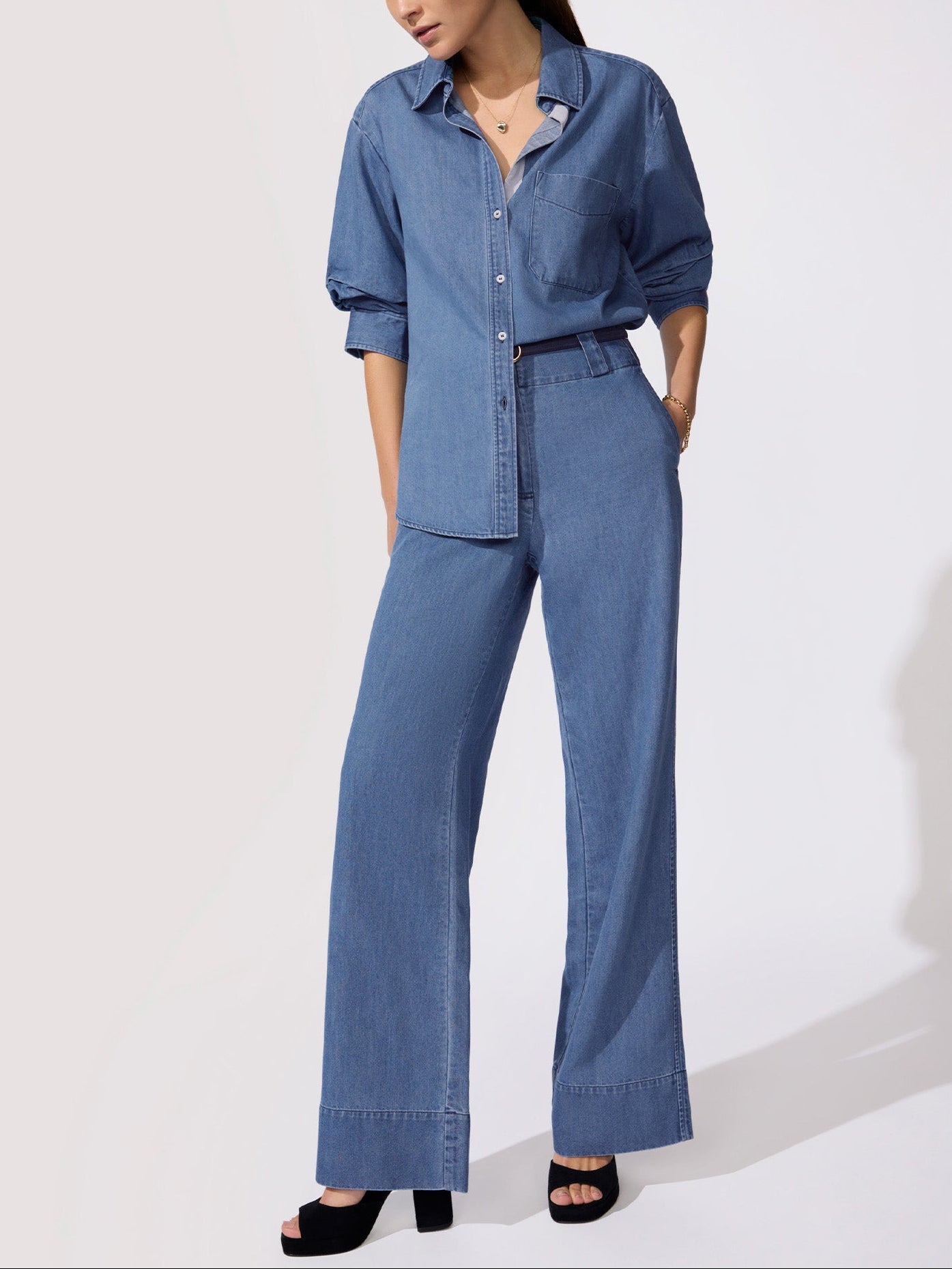 Classy and casual outfit featuring a chambray button-front shirt with chest pocket paired with wide-leg denim trousers and black heels.