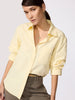 Yellow button down top in a relaxed cotton poplin with long sleeves, an open collar, and chest pocket tucked into olive trousers.