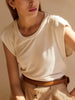 Cream crewneck t-shirt, tucked into beige pants with a brown belt
