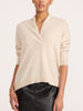 Front view of a woman wearing the Brochu Walker Siena Wrap Neck Cashmere Pullover in Stone Melange, a cream sweater with a split V-neck, paired with dark textured pants.