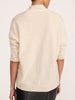 Back view of a woman wearing the Brochu Walker Siena Wrap Neck Cashmere Pullover in Stone Melange, a cream mock-neck sweater paired with dark textured pants.