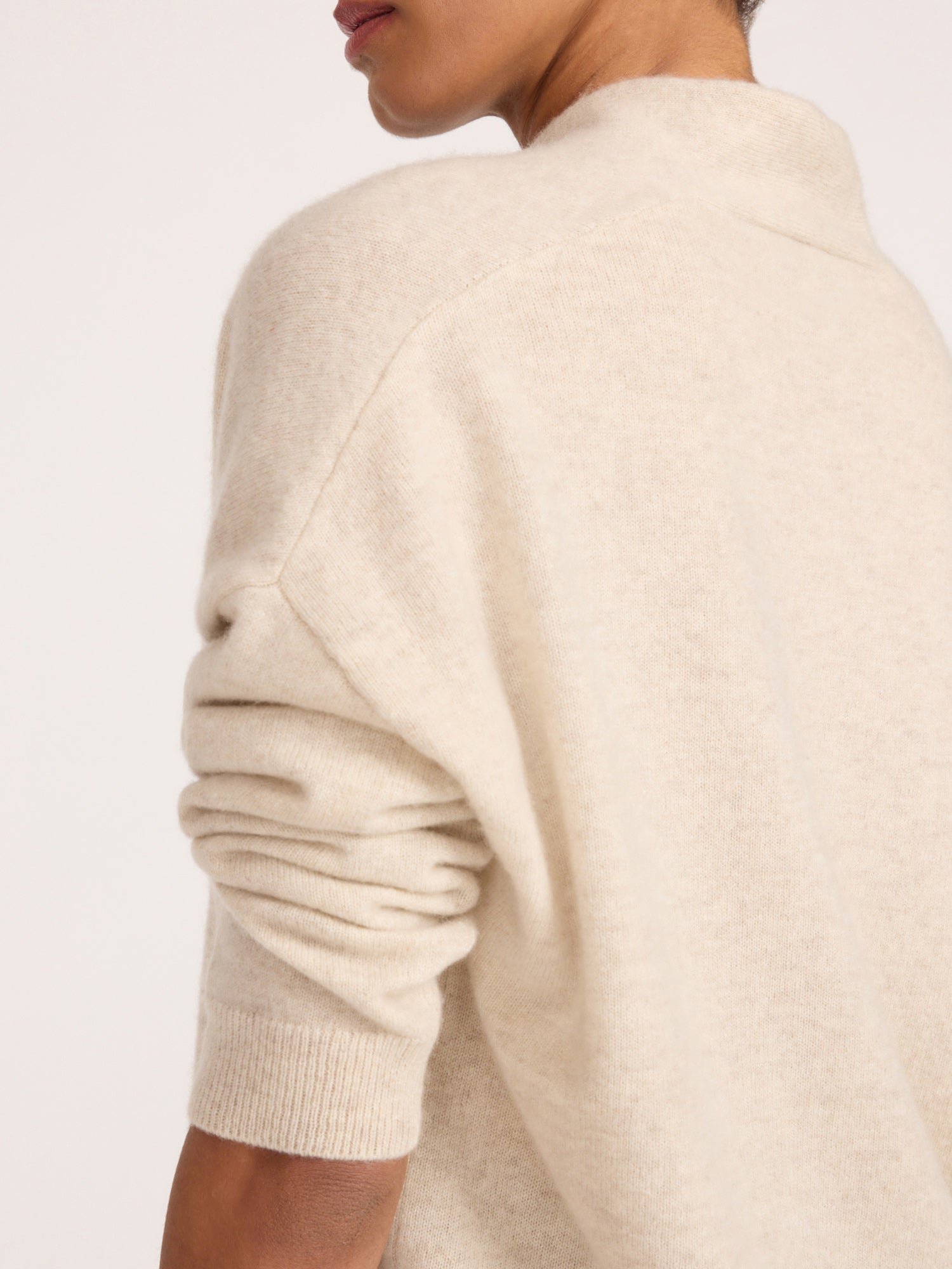 Close-up back and side view of the Brochu Walker Siena Wrap Neck Cashmere Pullover in Stone Melange, a cream knit sweater with a mock wrap neckline.