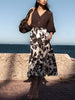 Woman wearing The Edda Printed Skirt, a black-and-white floral midi skirt, standing by the sea