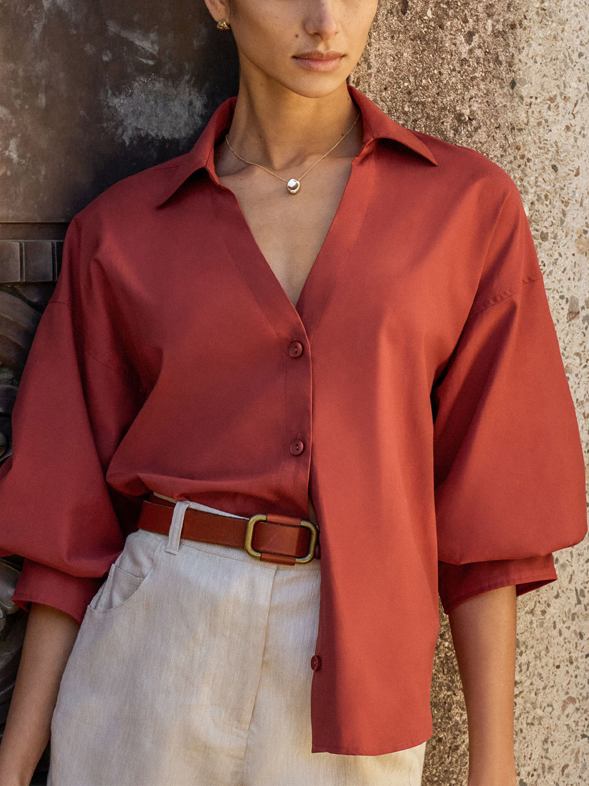 Woman wearing The Kate Shirt in Tuscany, a rust oversized button-down shirt tucked into cream trousers