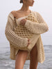 Woman on the beach wearing The Keifer Cardigan, a chunky cream crochet cardigan, over a swimsuit