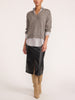 Woman wearing the pullover v-neck sweater in otter melange with flint stripe, styled with a black textured midi skirt and beige over-the-knee boots.