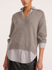 Woman wearing the pullover v-neck sweater in otter melange with flint stripe, layered over a striped button-down shirt with textured black pants.