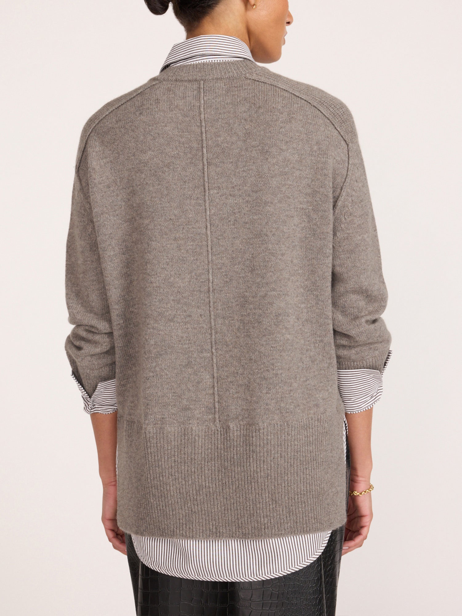 Back view of a woman wearing a pullover v-neck sweater in otter melange with flint stripe, layered over a striped shirt.