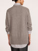 Back view of a woman wearing a pullover v-neck sweater in otter melange with flint stripe, layered over a striped shirt.